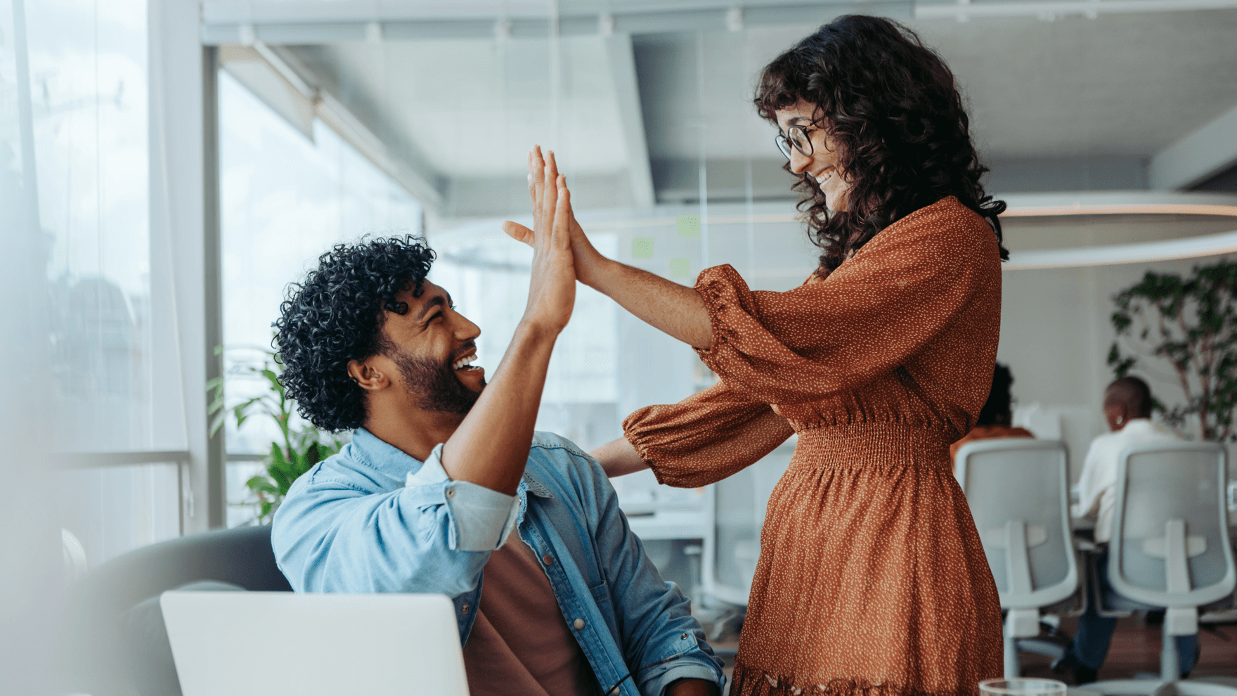 Young business people celebrating success with a high five in an office