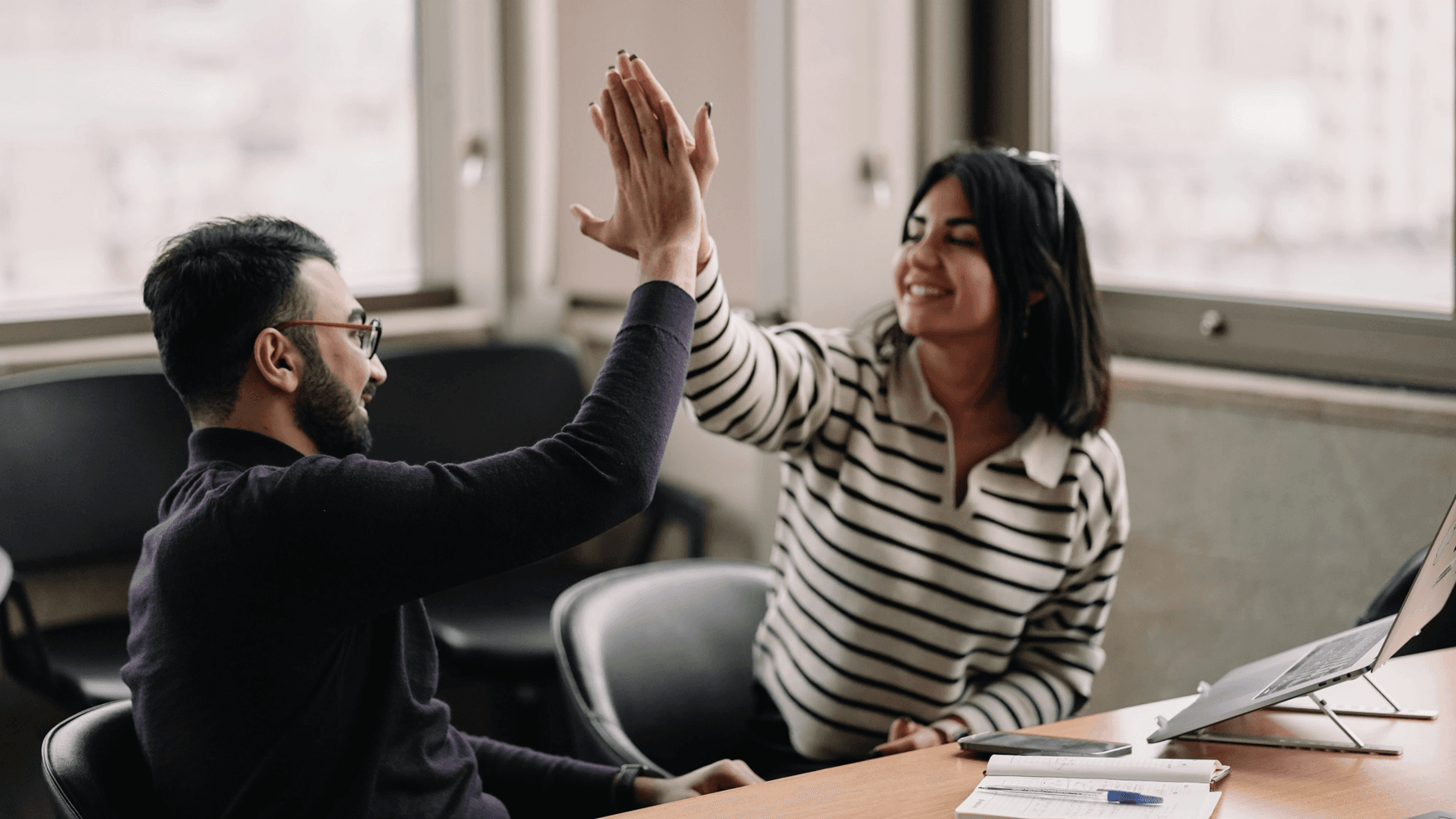 Man and woman high-fiving in the office