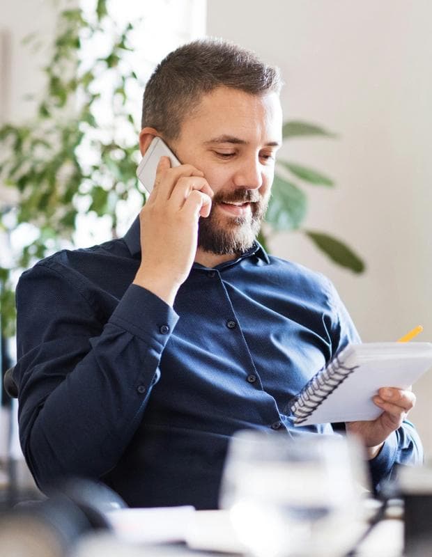 Man speaking on the phone holding notepad