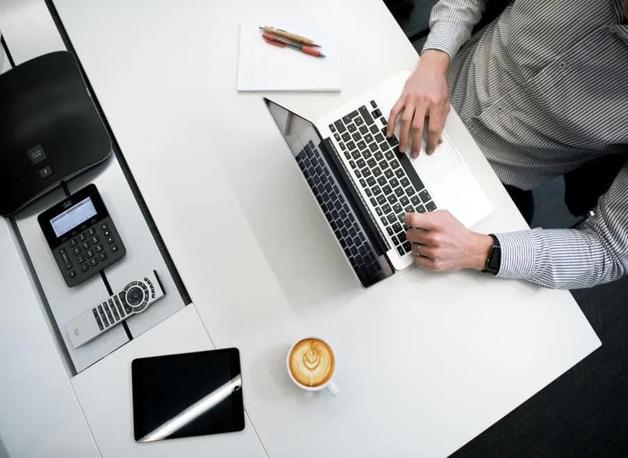 A man working on his laptop, a cup of coffee, and a calculator