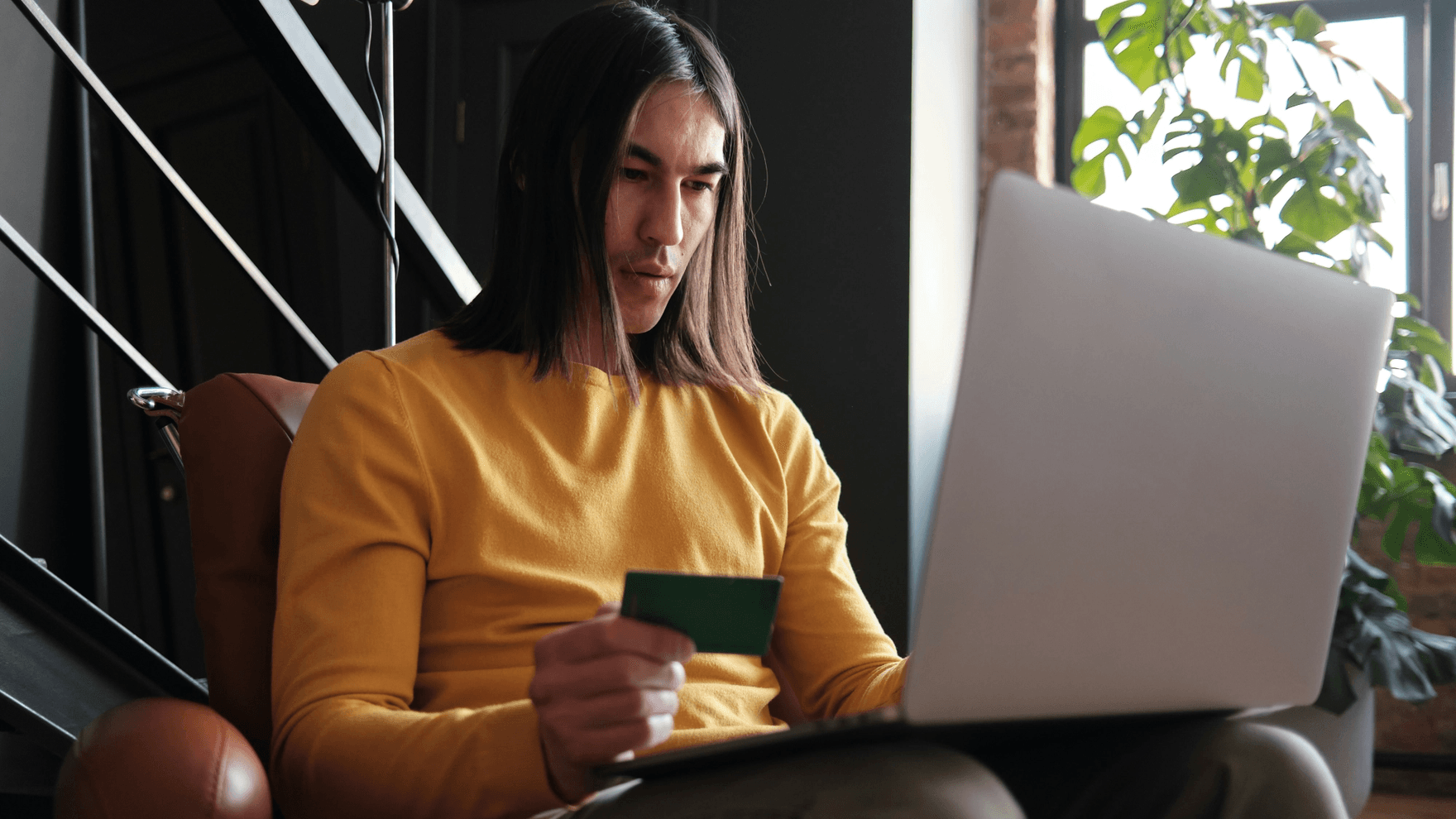 Man holding a credit card and typing on computer