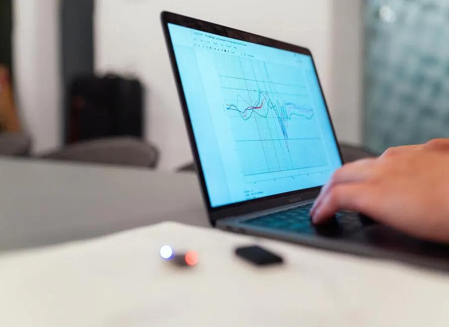 Fingers typing on a laptop, displaying a line graph