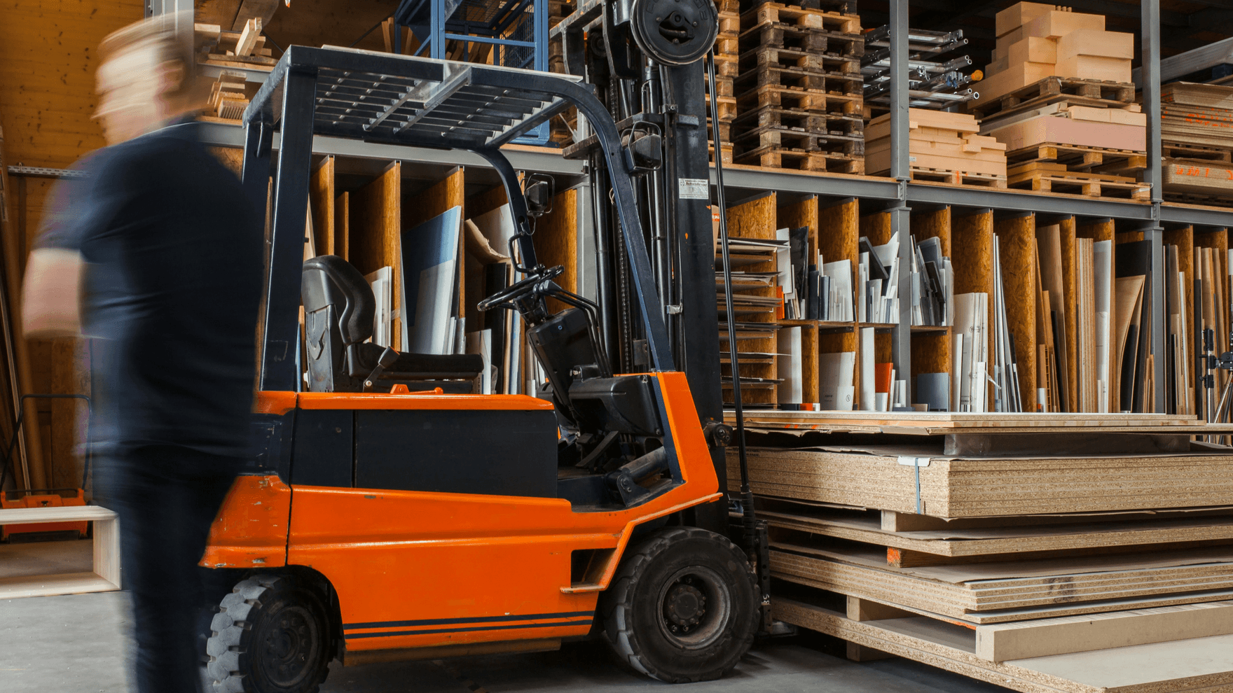 A forklift carrying stacks of wood in a warehouse