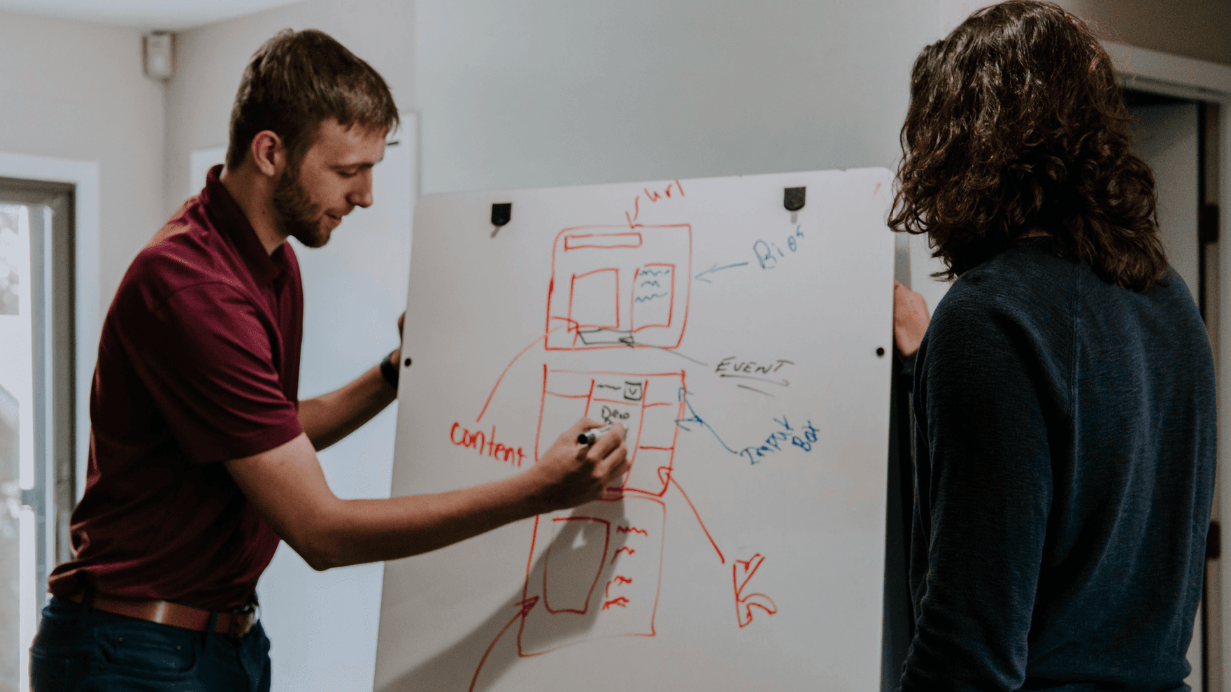 A man drawing a diagram while a colleague watches