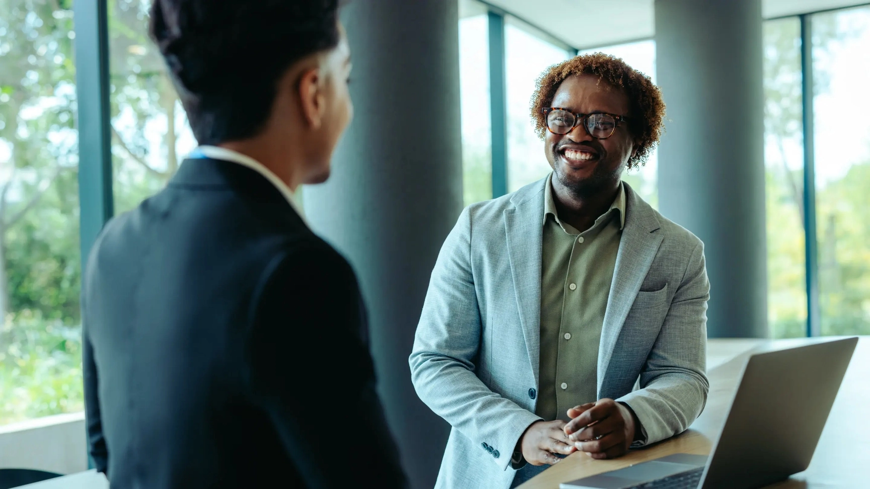 Two people having a discussion over a notebook and a laptop