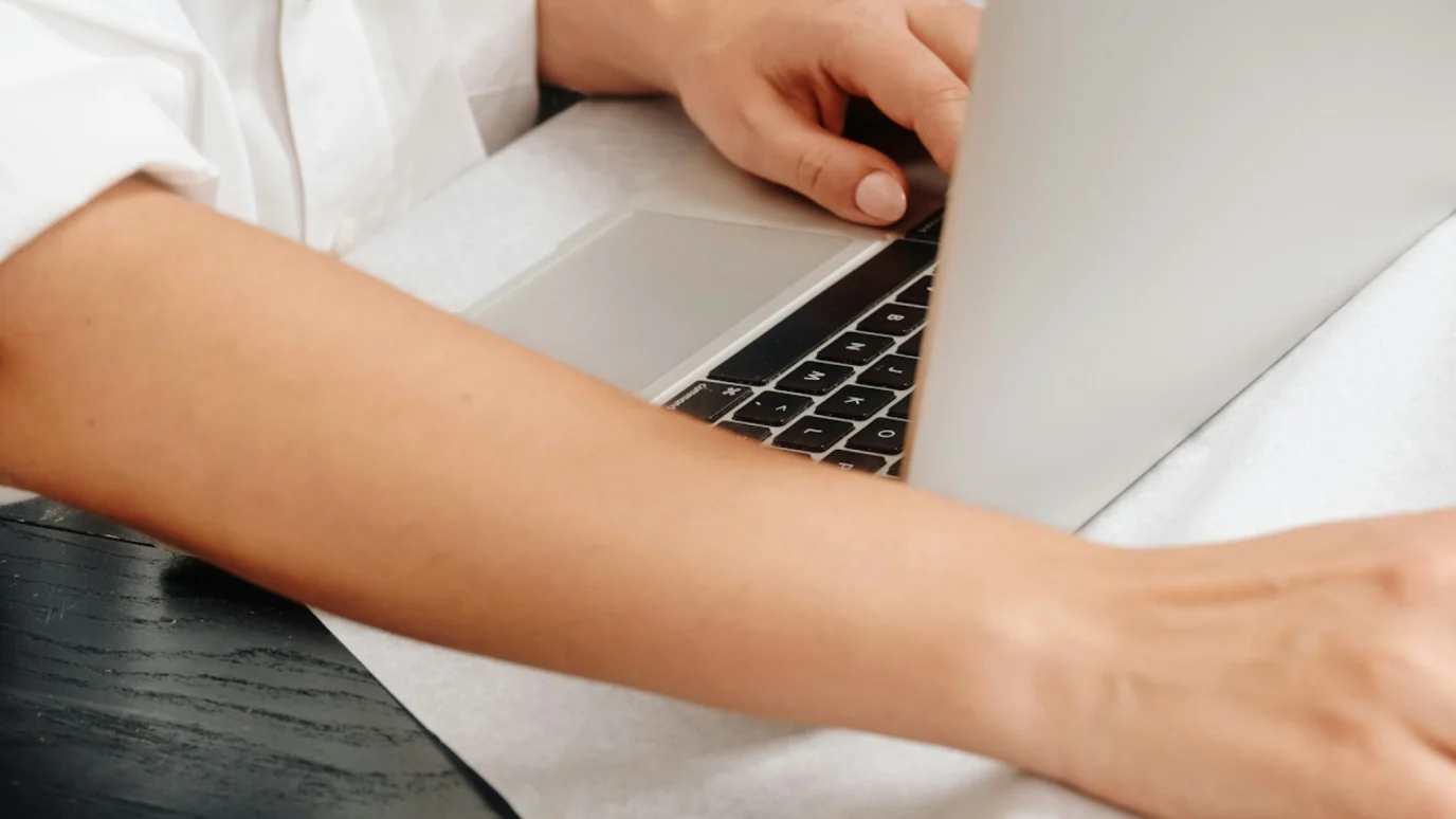 Close-up of hands typing on a modern silver laptop keyboard, symbolizing focused digital execution, coding, marketing, or business planning within an accelerator environment.