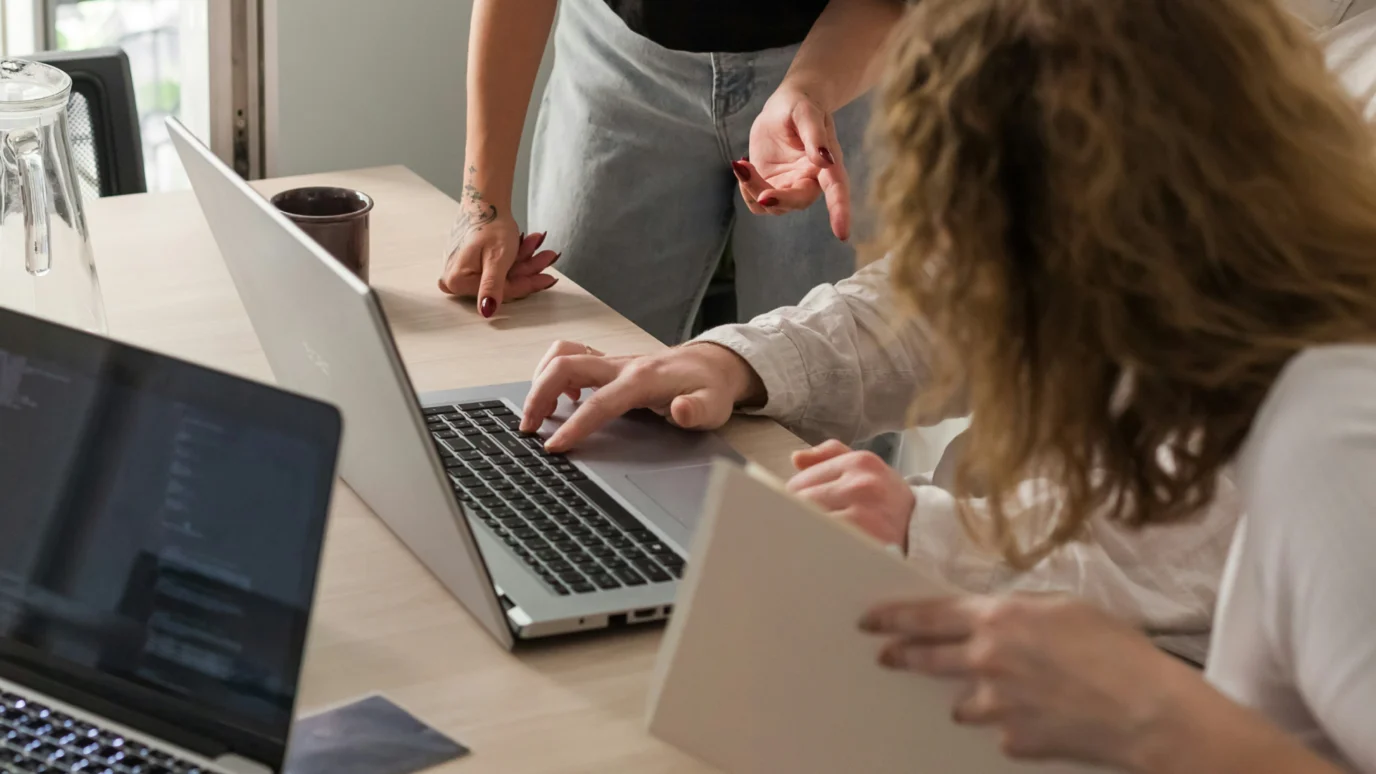Two entrepreneurs or founders working together on a laptop, discussing business plans, technical execution, or digital marketing during an accelerator program session.