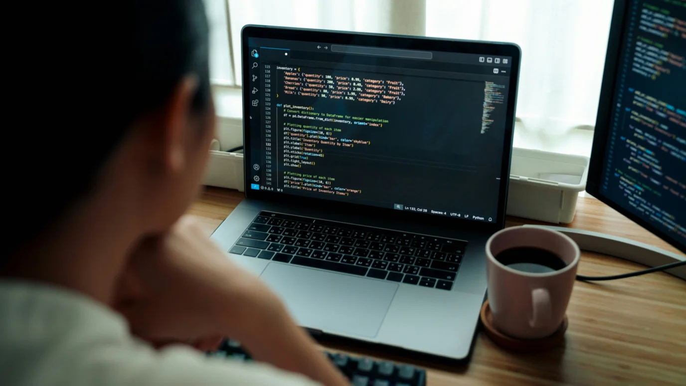 Entrepreneur or engineer writing Python code for inventory or product data on a laptop, emphasizing the technical skills and back-end development crucial for building and scaling a startup.