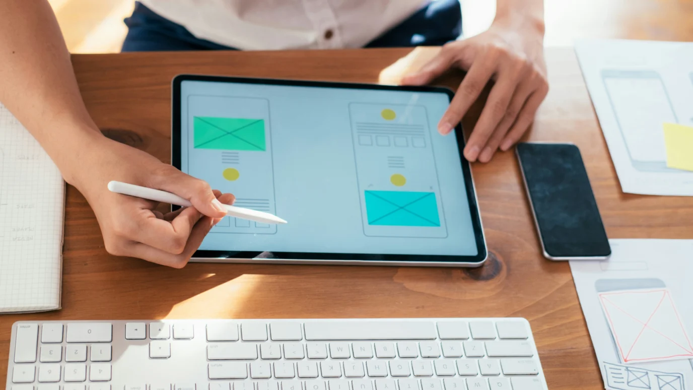 Person sketching a digital wireframe on a tablet.