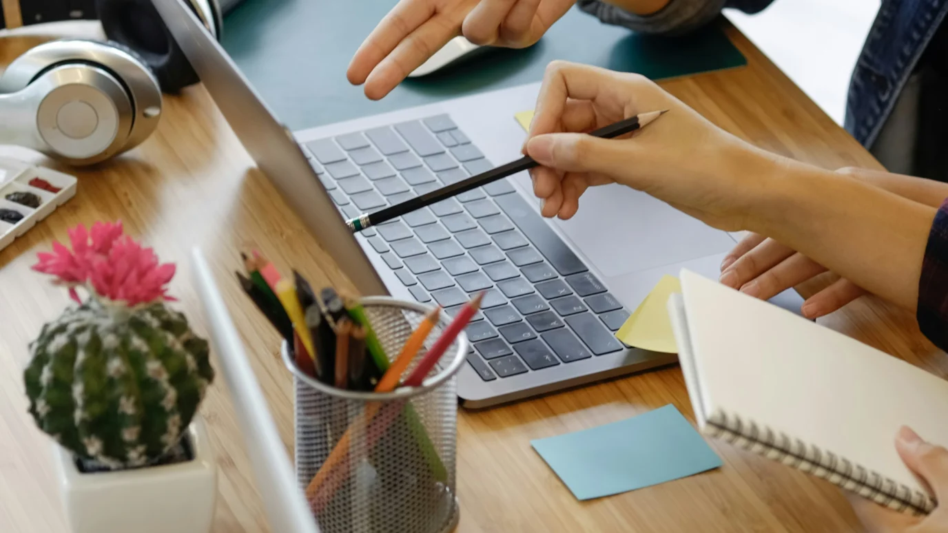 Two people discussing design work on a laptop, pointing at the screen.