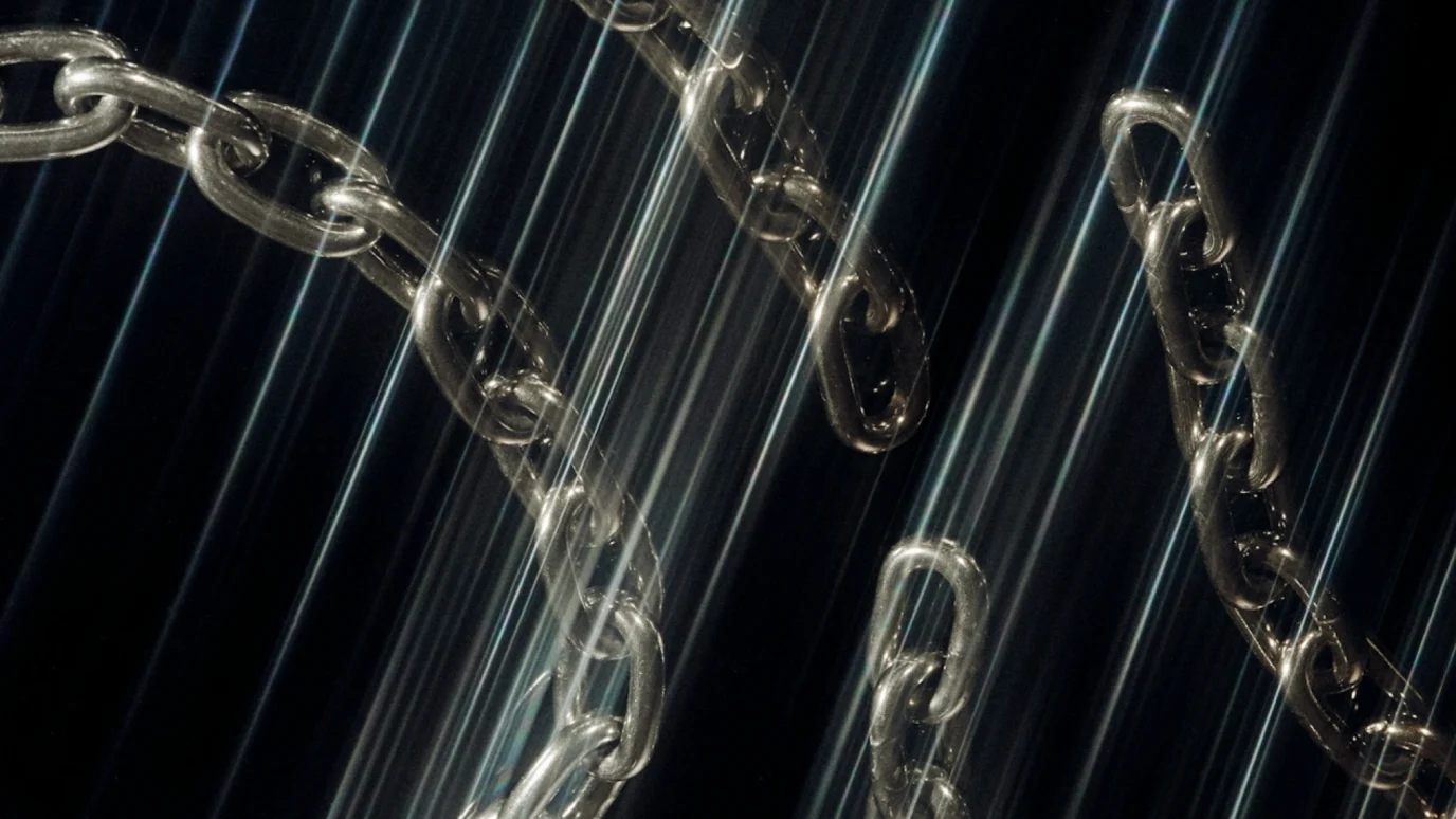 Close-up of shiny metal chains with dramatic, reflective lighting effects.