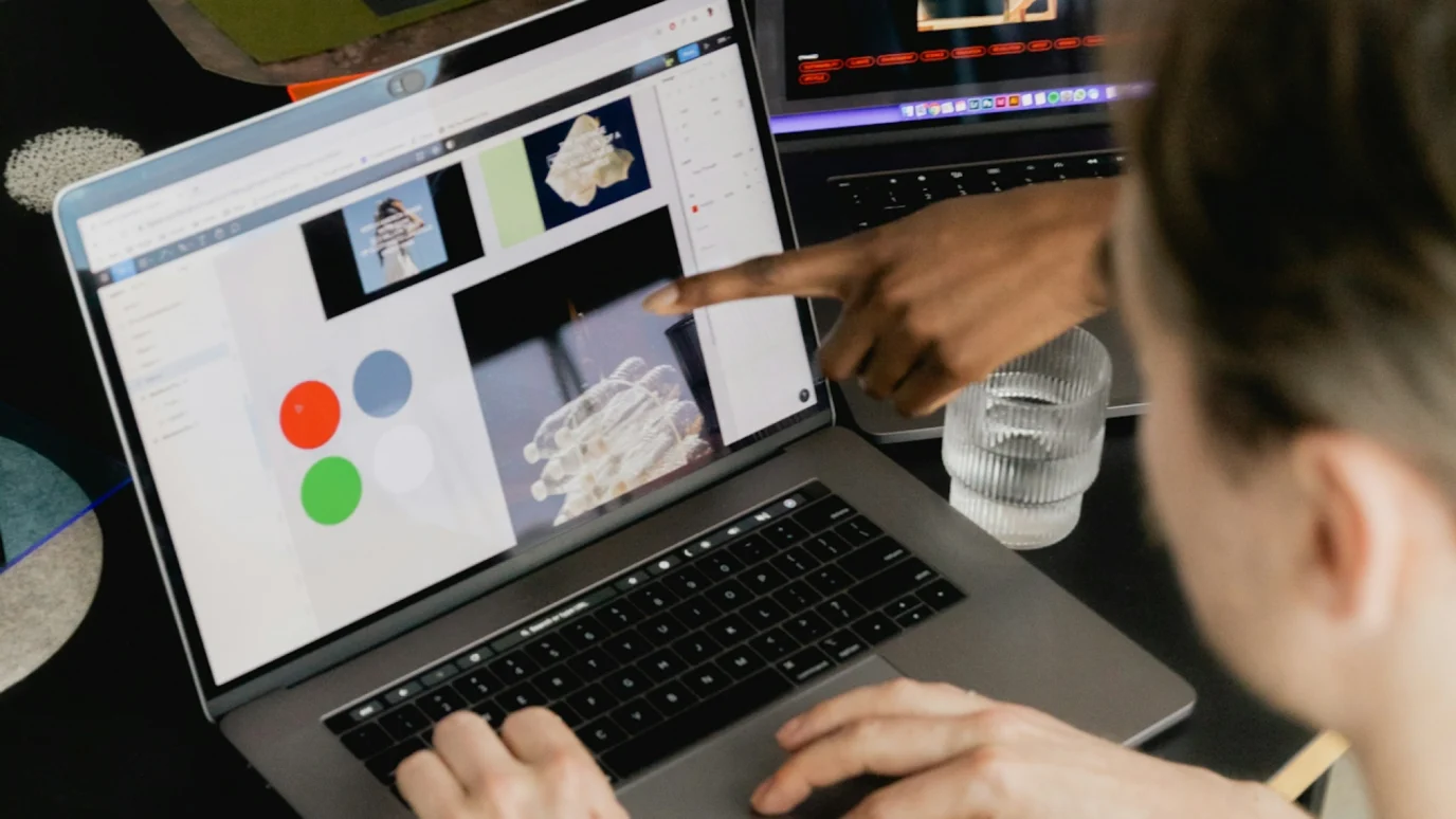 Two people collaborating on a digital design project on a laptop.