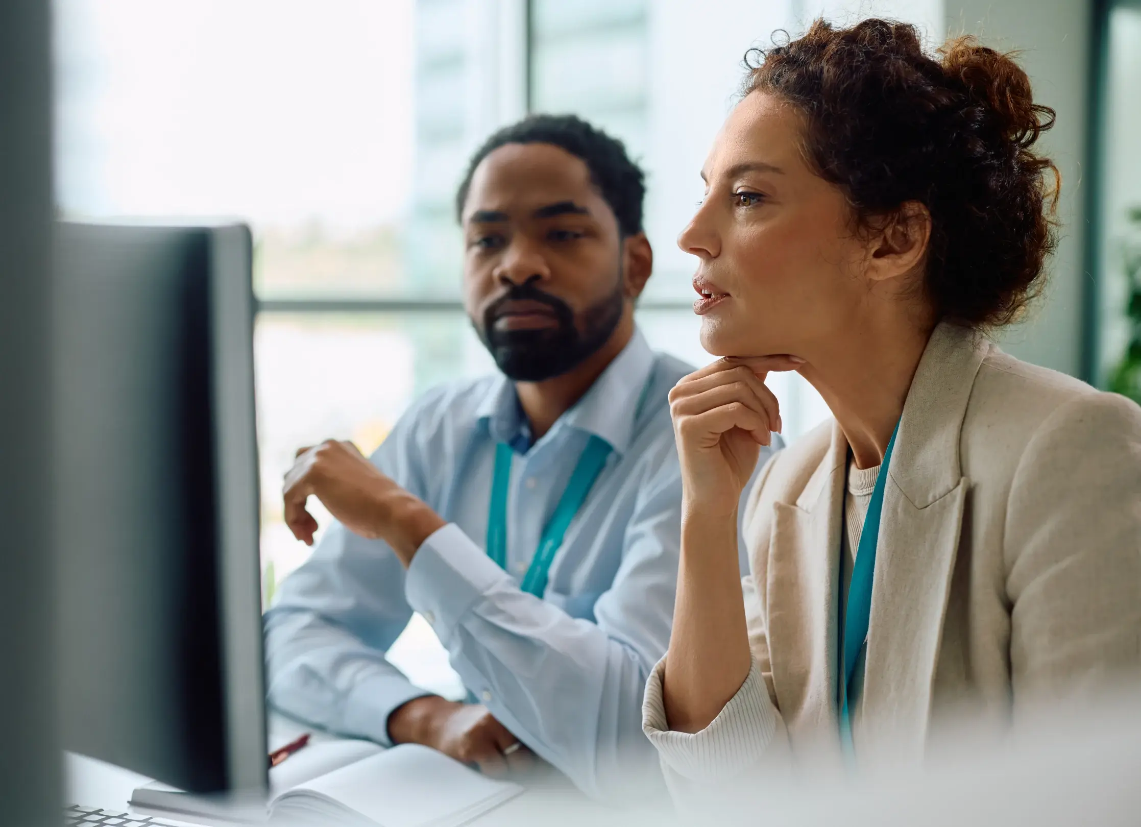 Business colleagues analyzing data and navigating AI software on a desktop monitor in a modern office.